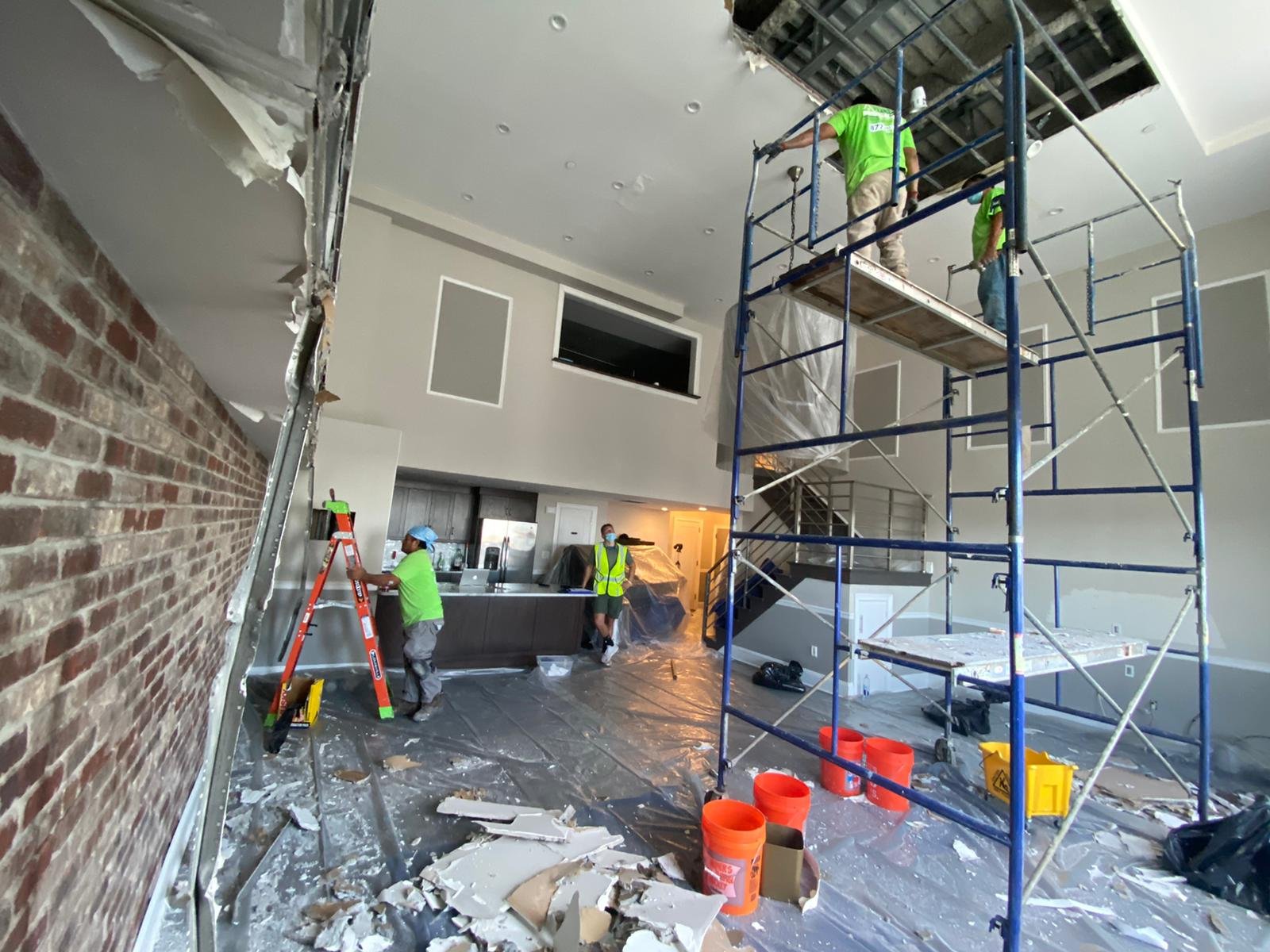 Three Anajur Construction crew members performing coordinated demolition with scaffolding and exposed brick on a Staten Island restoration job